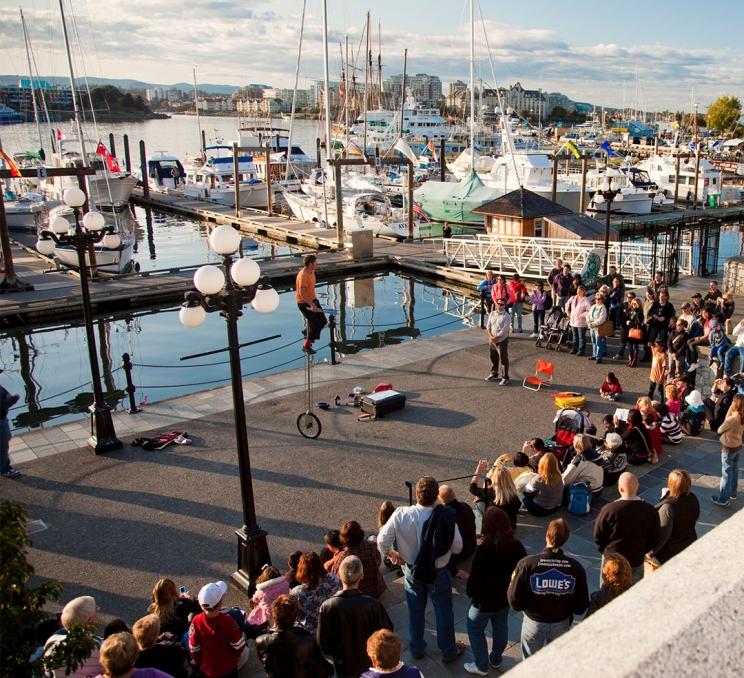 A unicyclist performs a busker show on the Lower Causeway of the Inner Harbour in Victoria, BC