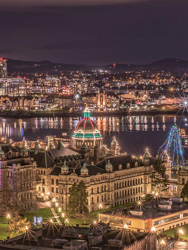 An aerial view of the BC Parliament Buildings and the Inner Harbour looking toward Vic West during the holiday season in Victoria, BC