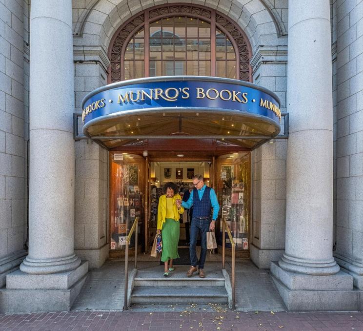 A couple walks hand-in-hand out of Munro's Books, a bookstore located on Government Street in Victoria, BC