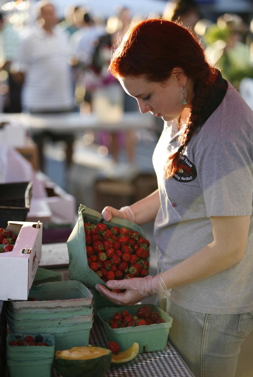 A woman sorts strawberries at a Farmers Market in Victoria, BC