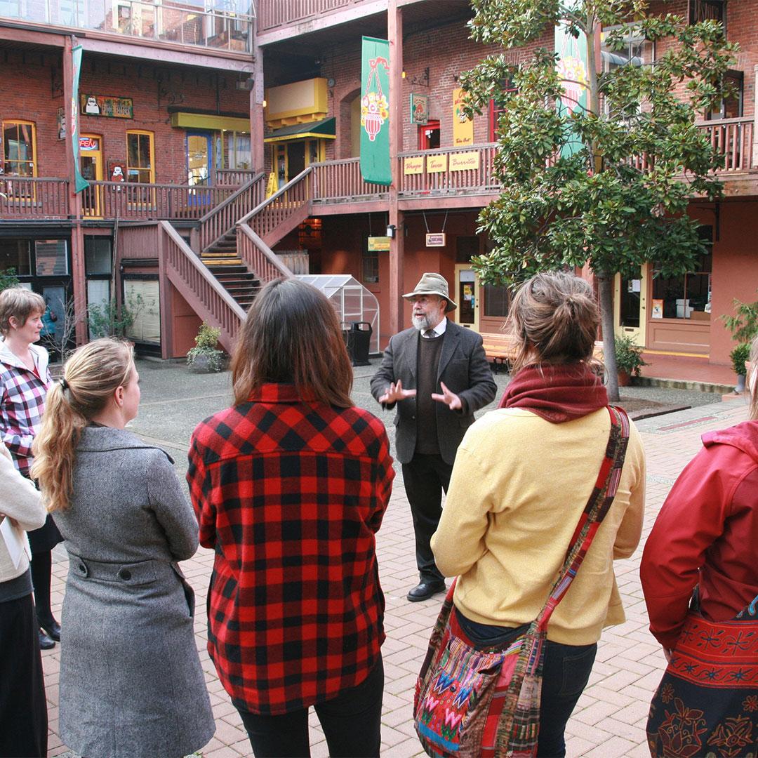 A walking tour guide from Discovery Walks provides information to guests in Market Square in Victoria, BC