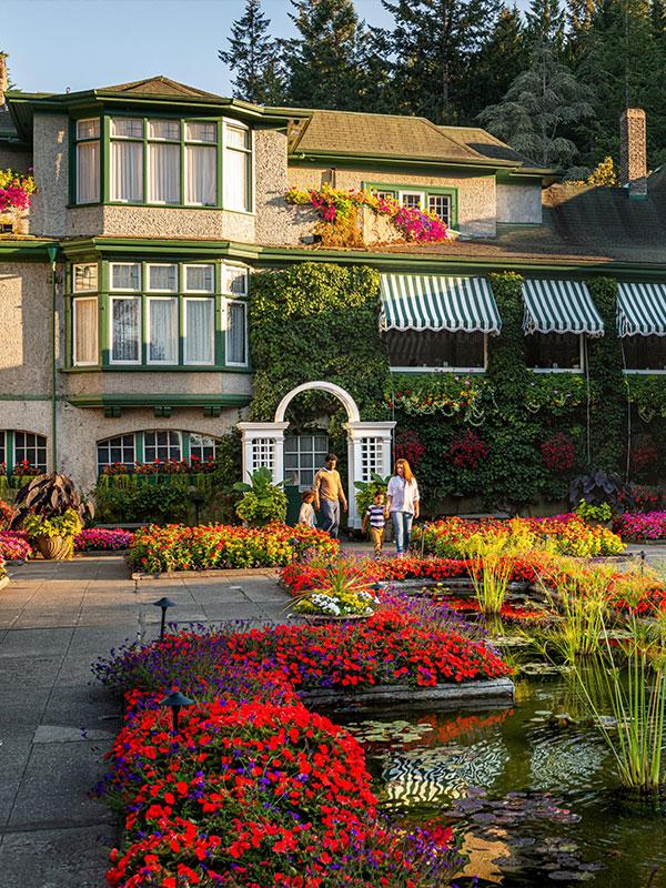A young family walks hand-in-hand through The Butchart Gardens' Rose Garden in Victoria, BC