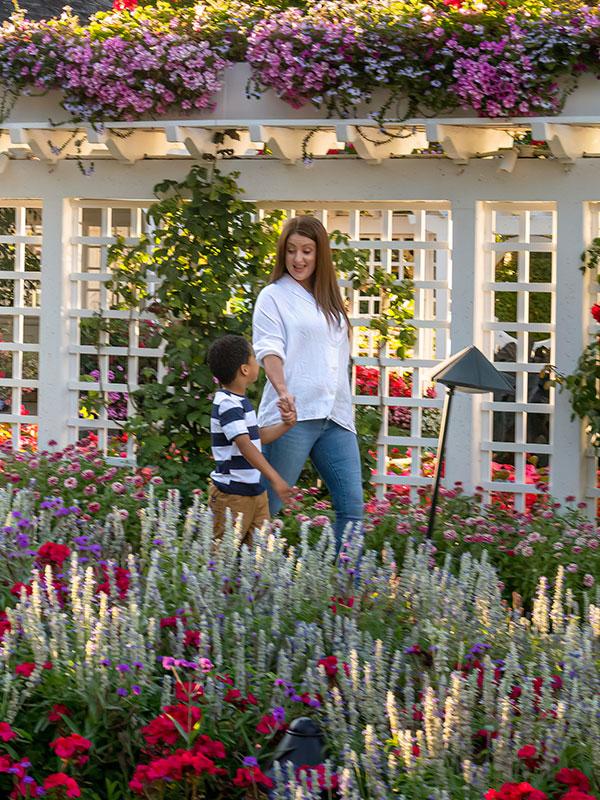 A mother and her son walk hand-in-hand through flowers at The Butchart Gardens