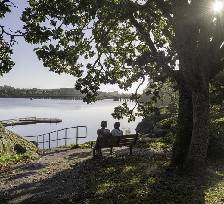 A couple sits on a park bench overlooking the Gorge Waterway in Banfield Park in Victoria, BC's Vic West neighbourhood