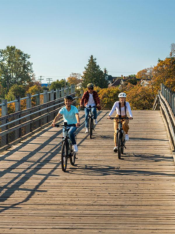 A group of three cyclists ride bikes along the Selkirk Trestle from Victoria, BC's Vic West neighbourhood
