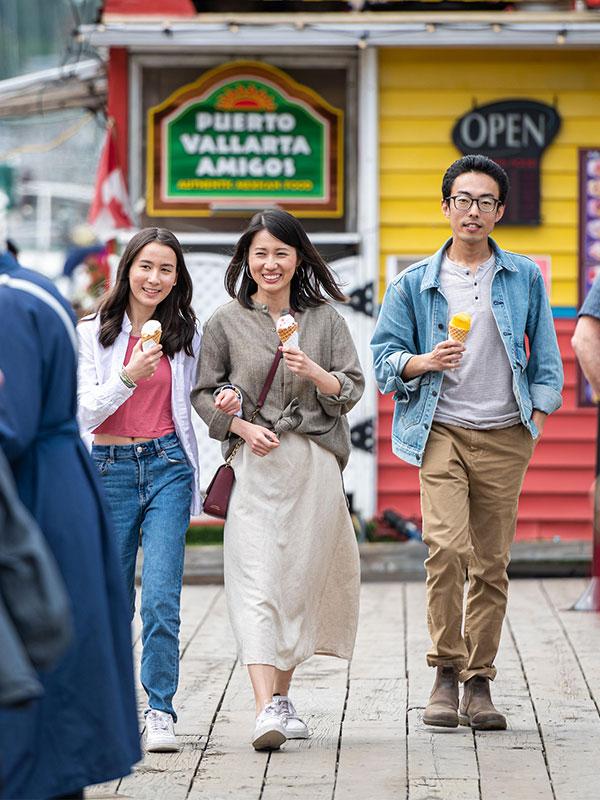 A young family eating ice cream cones walks along the dock at Fisherman's Wharf, a vibrant floating neighbourhood, in Victoria, BC