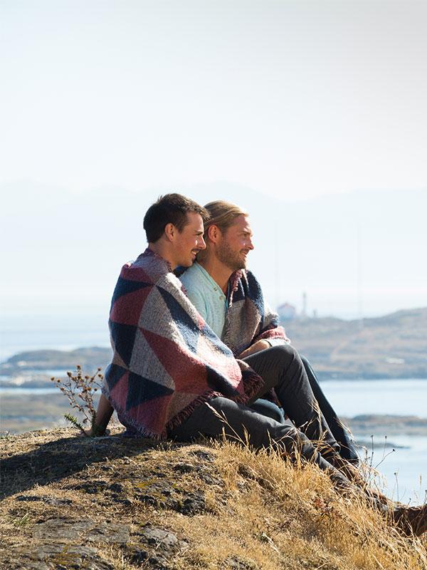 A male couple sits in a park and looks out over the Salish Sea in Victoria, BC