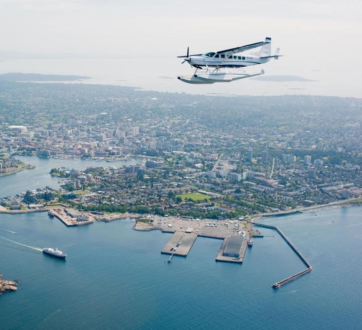 Seair Seaplanes aircraft flying over Victoria BC harbour and coastline on Vancouver Island