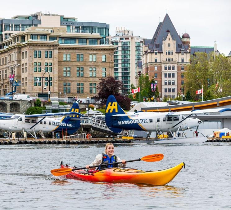 A solo kayaker paddles on Victoria, BC's Inner Harbour past the seaplane terminal