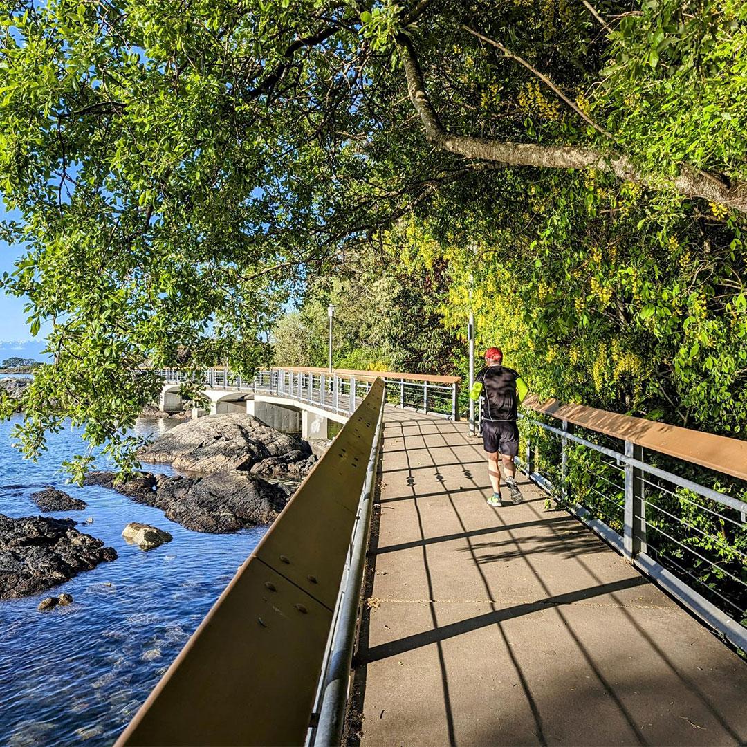 A person runs along the West Bay Walkway waterfront in the Vic West neighbourhood of Victoria, BC