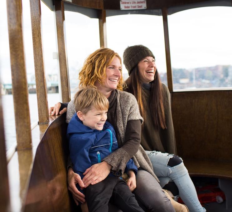 A female couple and their son ride a Victoria Harbour Ferry across the Inner Harbour in Victoria, BC