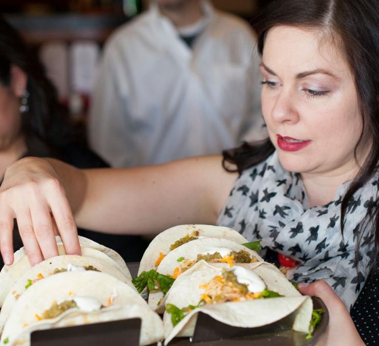 A woman on a food tour grabs a taco from a tray in Victoria, BC