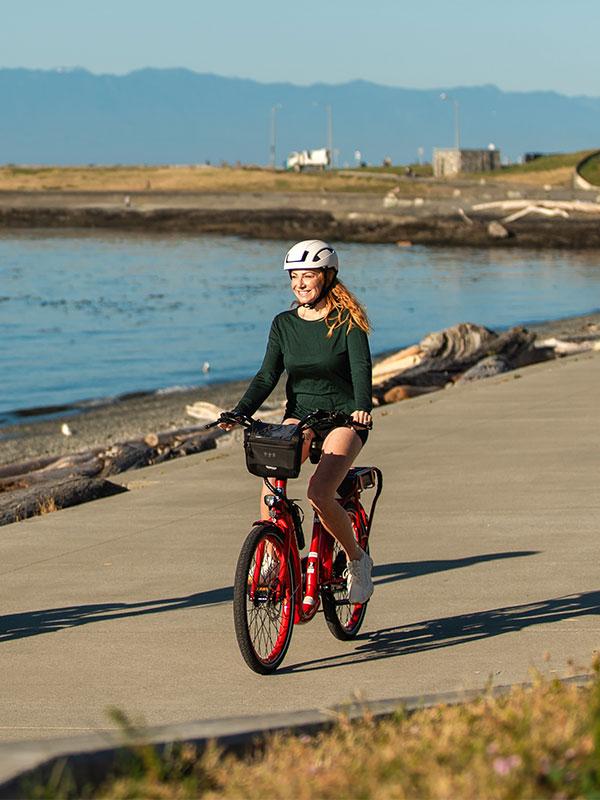 A woman riding a bike along the waterfront off of Dallas Road in Victoria, BC