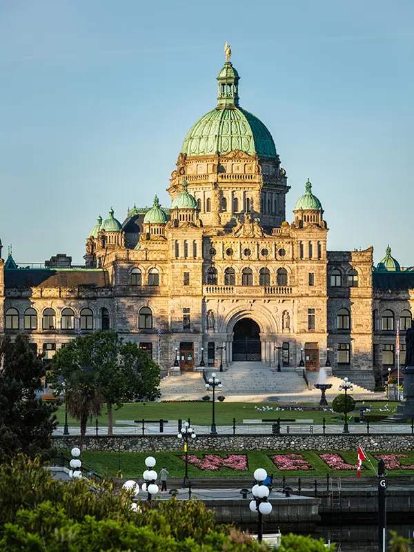 The BC Parliament Buildings illuminated by a sunrise as seen from across the Inner Harbour in Victoria, BC