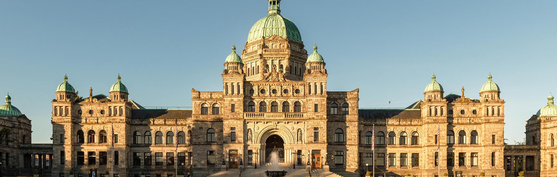 The BC Parliament Buildings in Victoria, BC are illuminated by a sunrise