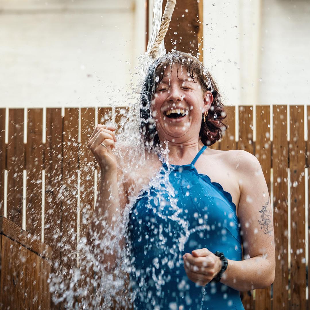 A woman does a cold plunge bucket at Aerth Saunas in Victoria, BC