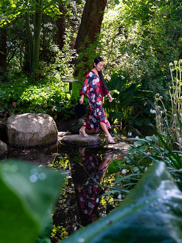 A woman walks across stones on a pond in Finnerty Gardens at the University of Victoria in Victoria, BC