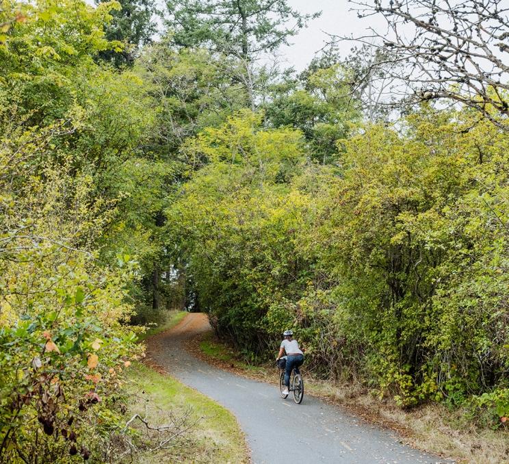 A cyclist rides along a wooded bike path in Victoria, BC