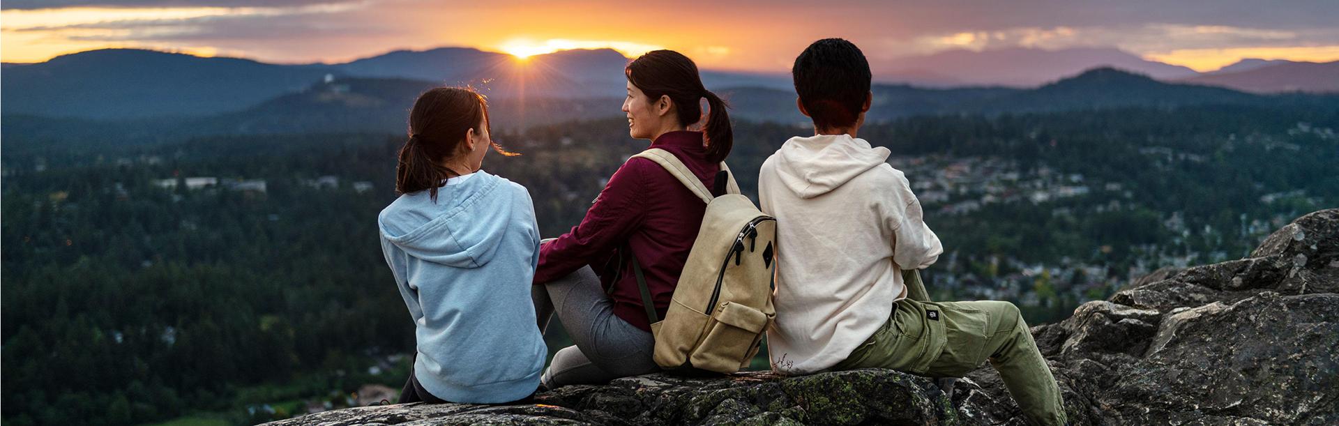 A family sits atop PKOLS (formerly Mount Douglas) to watch the sun set above Greater Victoria, BC