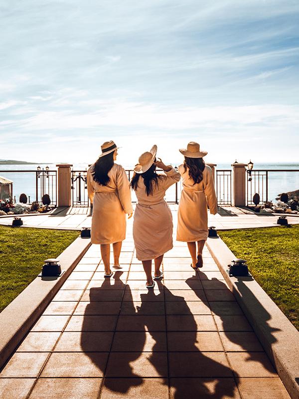 A group of women walking out toward the spa while wearing robes at the Oak Bay Beach Hotel in Victoria, BC