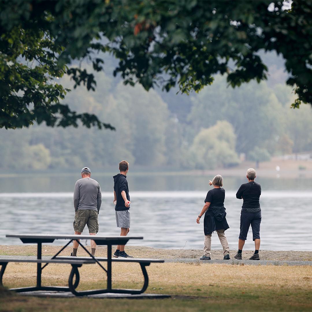 A group of people look out over the water at Elk/Beaver Lake Regional Park in Saanich, BC
