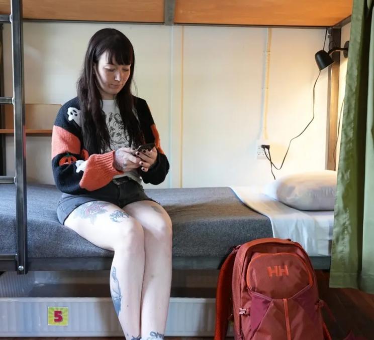A backpacker sits on a bed in her suite at Ocean Island Inn Backpackers Suites in Victoria, BC