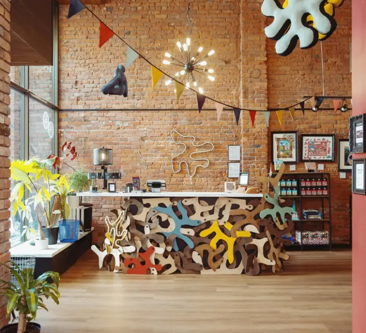 The interior of Puzzle Lab featuring exposed brick walls, colourful puzzle-shaped décor, creative lighting, and a custom-designed front counter.