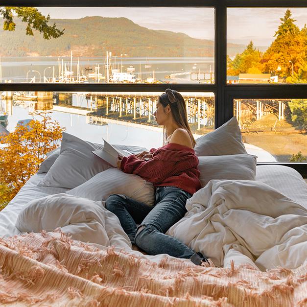 A woman reads a book while resting on her bed at the Brentwood Bay Resort on the Saanich Peninsula in Greater Victoria, BC during autumn