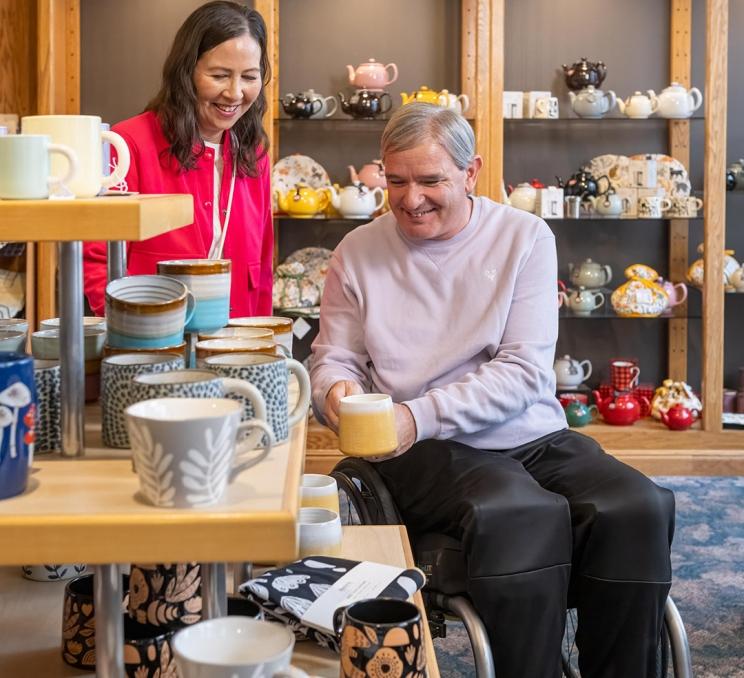 A couple with accessibility needs shops for mugs at Murchie's Tea & Coffee in Victoria, BC