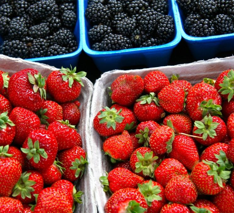 Fresh strawberries and blackberries displayed in containers at a local market in Greater Victoria.