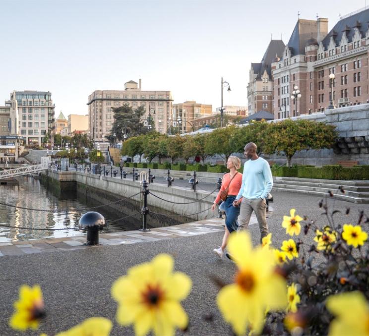 A couple walking along the waterfront in the Inner Harbour, Victoria, BC