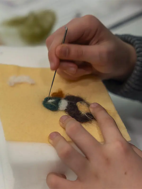 A person felts a duck during a felting workshop