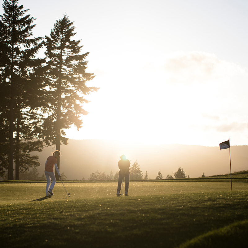 Two golfers at sunset on the green at the Westin Bear Mountain Golf Resort and Spa in Langford, British Columbia
