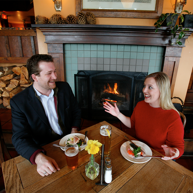 Couple Enjoys their Meal Fireside at Spinnakers Gastro Brewpub